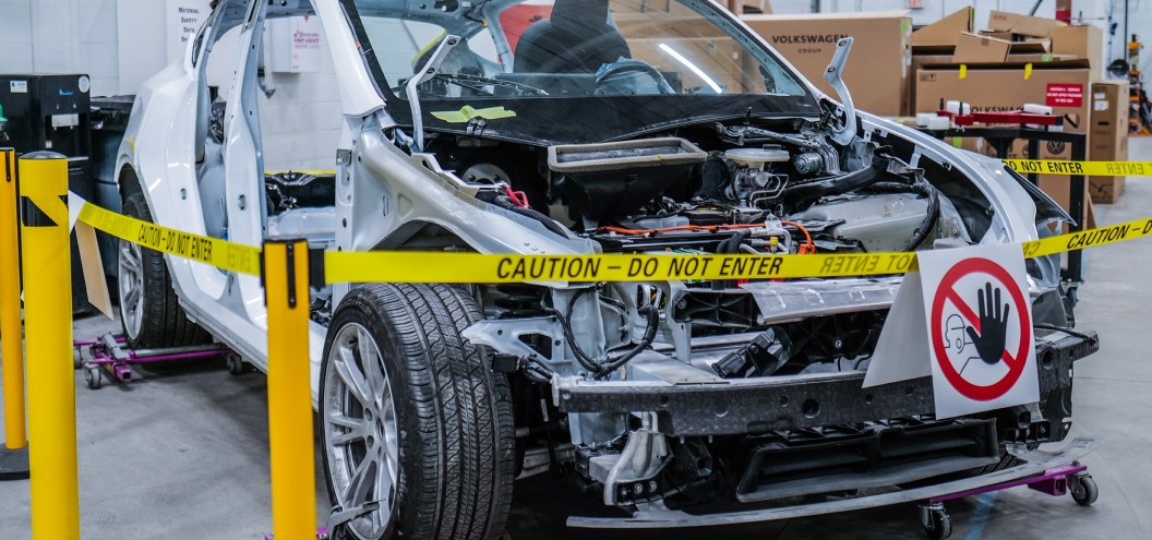 Electric car stripped for repair behind safety barriers